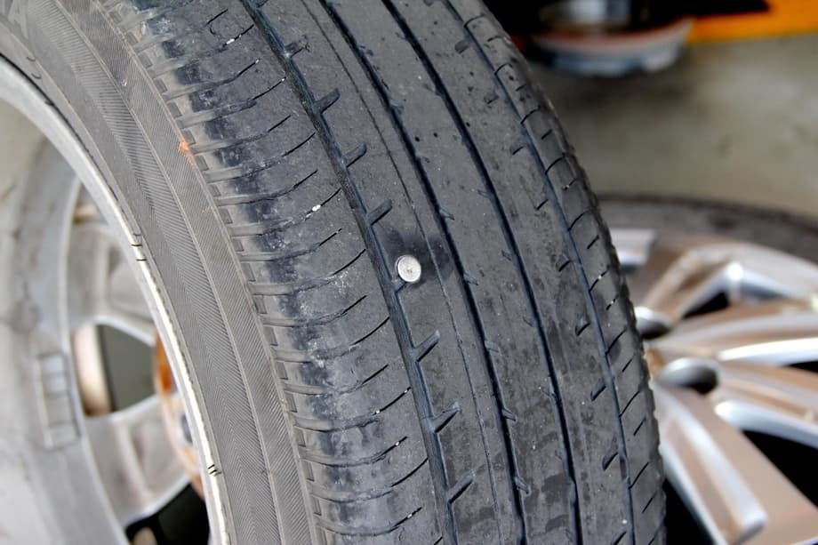 Ein mit einem Nagel durchstochener Reifen. Ist es eine Reparatur wert?